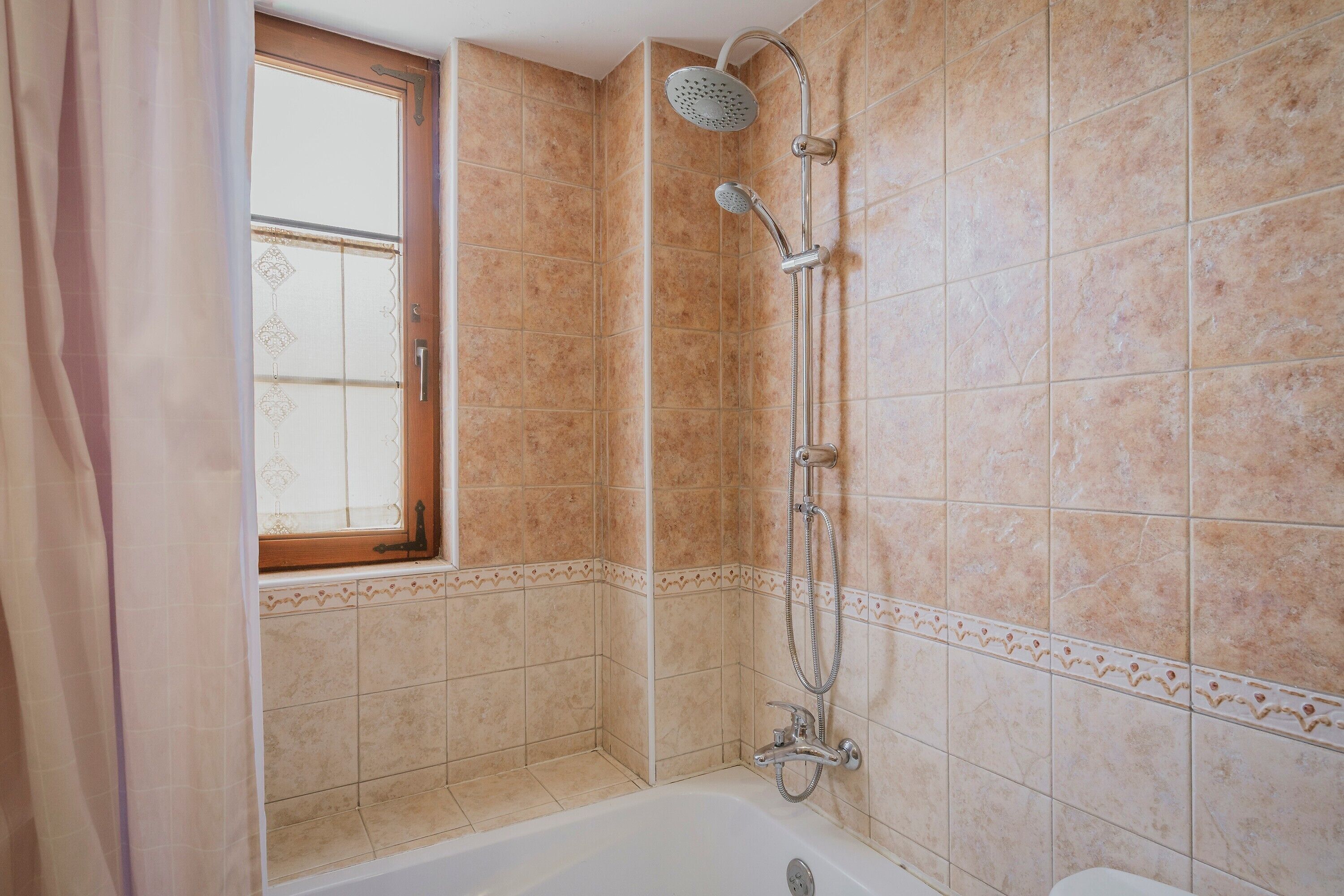 A bathroom with a bathtub, shower, and a window.