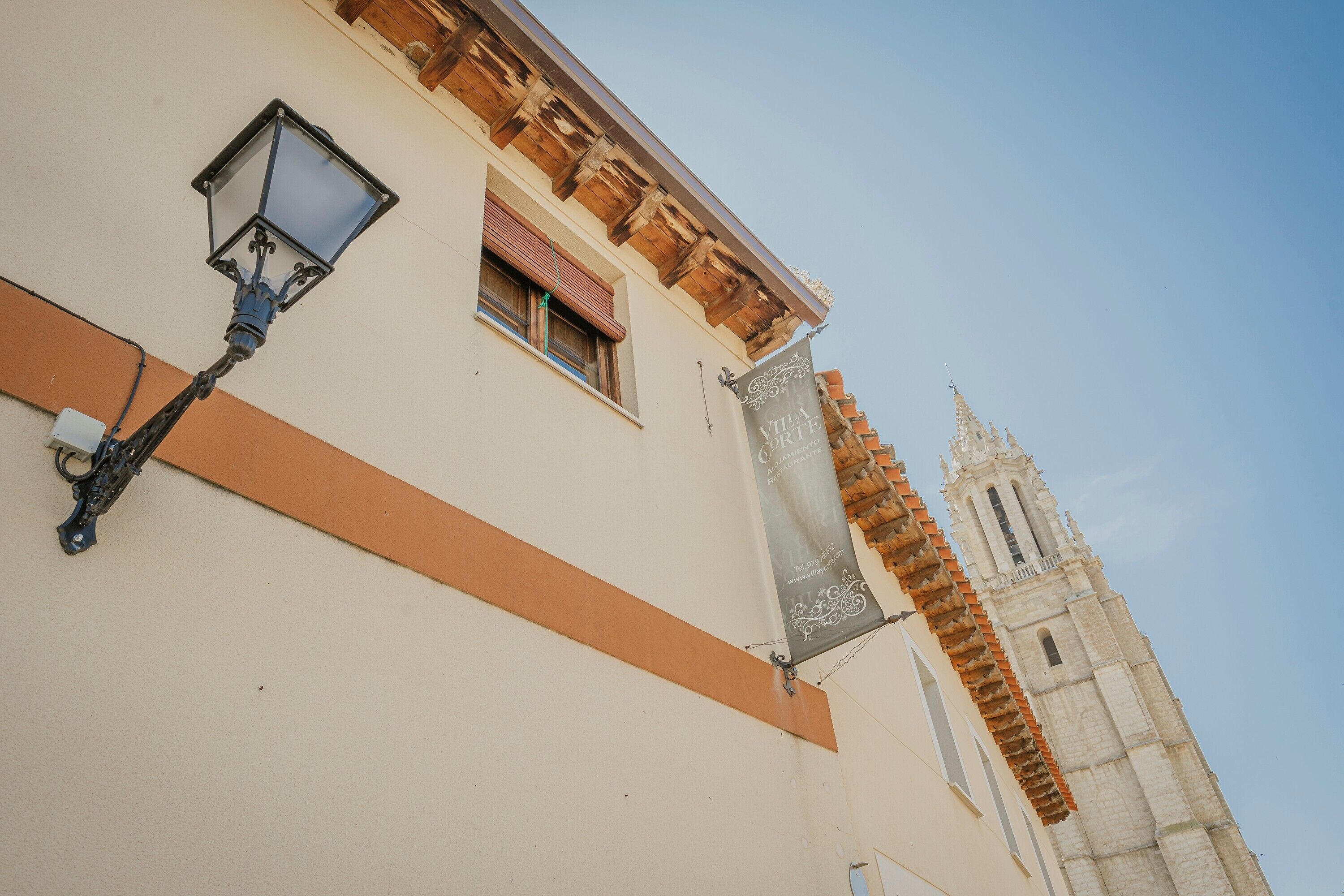 Un bâtiment avec un lampadaire, une fenêtre avec des volets et une banderole.