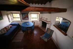 Een gezellige woonkamer met een blauwe bank, een ronde tafel en een open haard.