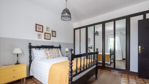 Un dormitorio con cama, mesita de noche, lámpara, armario y espejo.