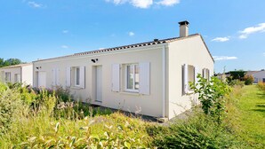 A row of white buildings with white shutters, surrounded by greenery.