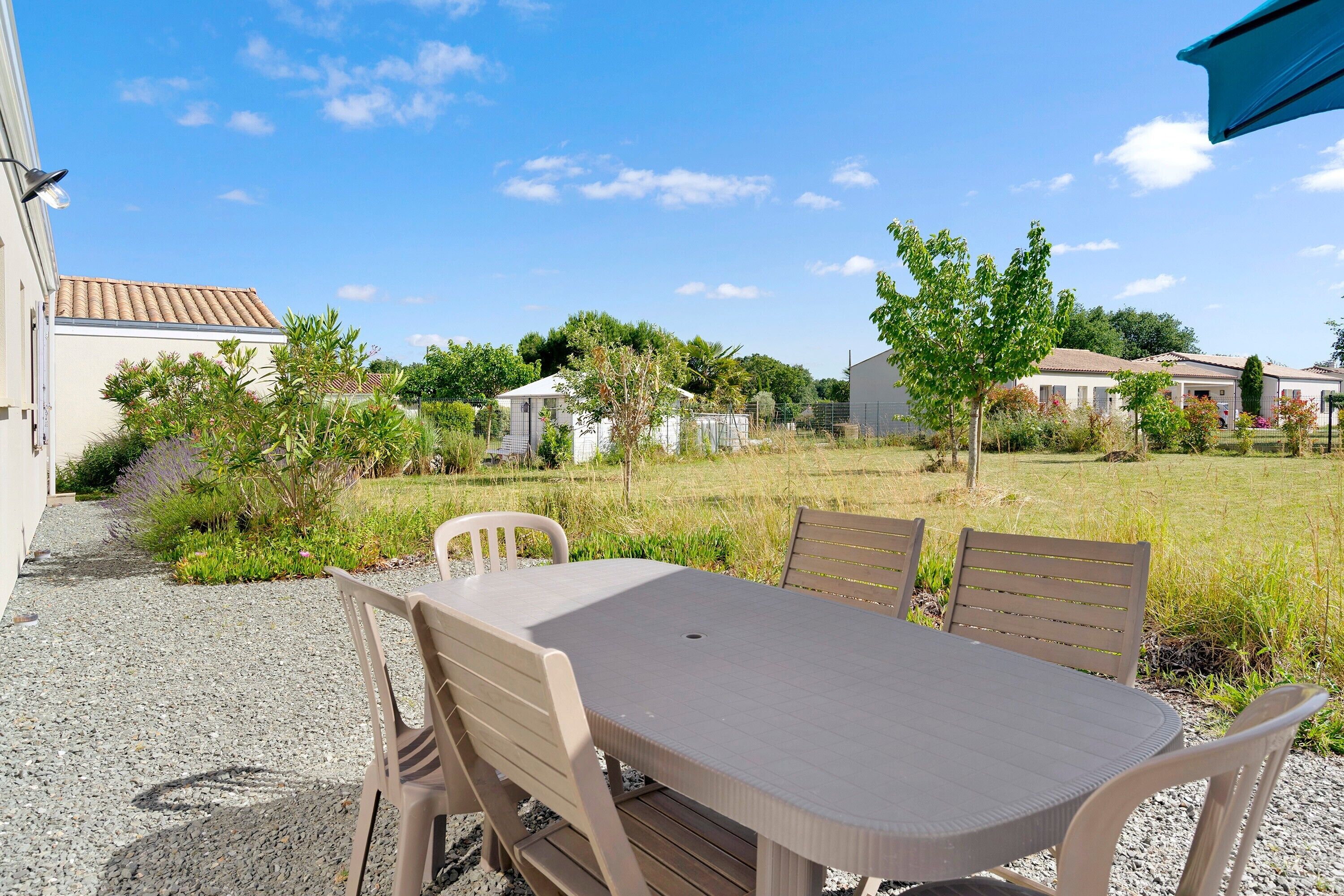 Eine Terrasse mit Tisch und Stühlen, umgeben von einem Kiesweg und Pflanzen.