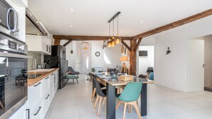 A modern kitchen with built-in appliances, a dining area with a wooden table and chairs, and exposed wooden beams on the ceiling.