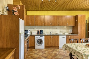 Une cuisine avec des meubles de rangement en bois, un lave-linge, un four à micro-ondes et un évier.