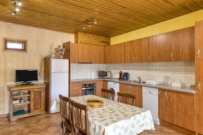 Une cuisine avec des meubles de rangement en bois, une table à manger avec des chaises, un réfrigérateur, un four à micro-ondes et un évier.