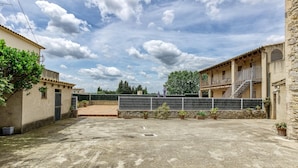A courtyard with a concrete floor, potted plants, and a metal fence. - Apartment 'Cal Ferrer 2 - Quadres' with Shared Pool, Wi-Fi and Air Conditioning (Unknown)