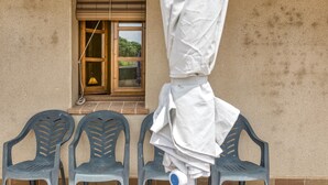 A building exterior with a window, a door, and a pile of white cloths on a chair. - Apartment 'Cal Ferrer 2 - Quadres' with Shared Pool, Wi-Fi and Air Conditioning (Unknown)