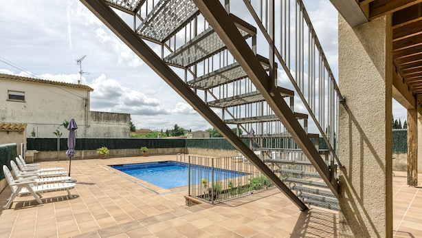A rooftop pool area with a staircase, lounge chairs, and a view of the surrounding buildings. - Apartment 'Cal Ferrer 2 - Quadres' with Shared Pool, Wi-Fi and Air Conditioning (Unknown)