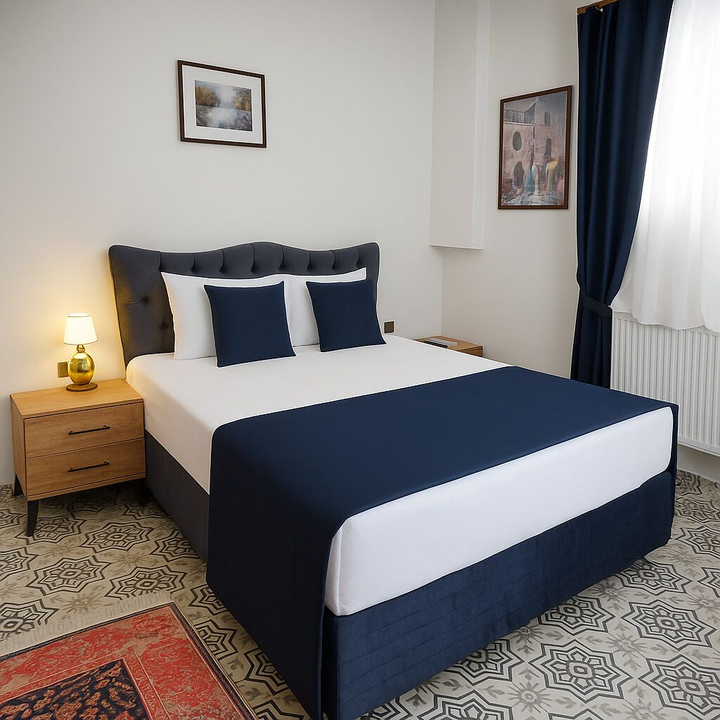 A neatly arranged hotel room with a large bed, bedside tables, a lamp, and two framed pictures on the wall.