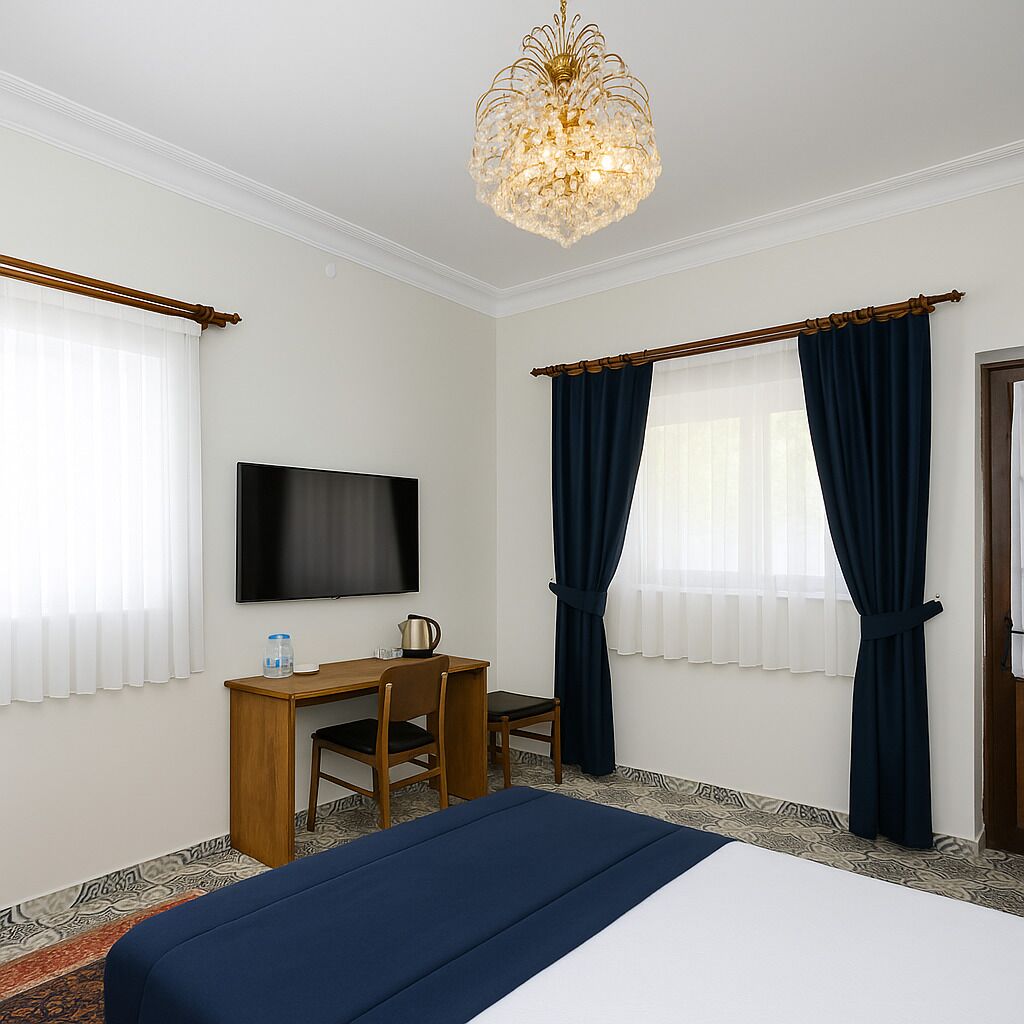 A hotel room with a bed, a desk with a chair, a television, and a chandelier.