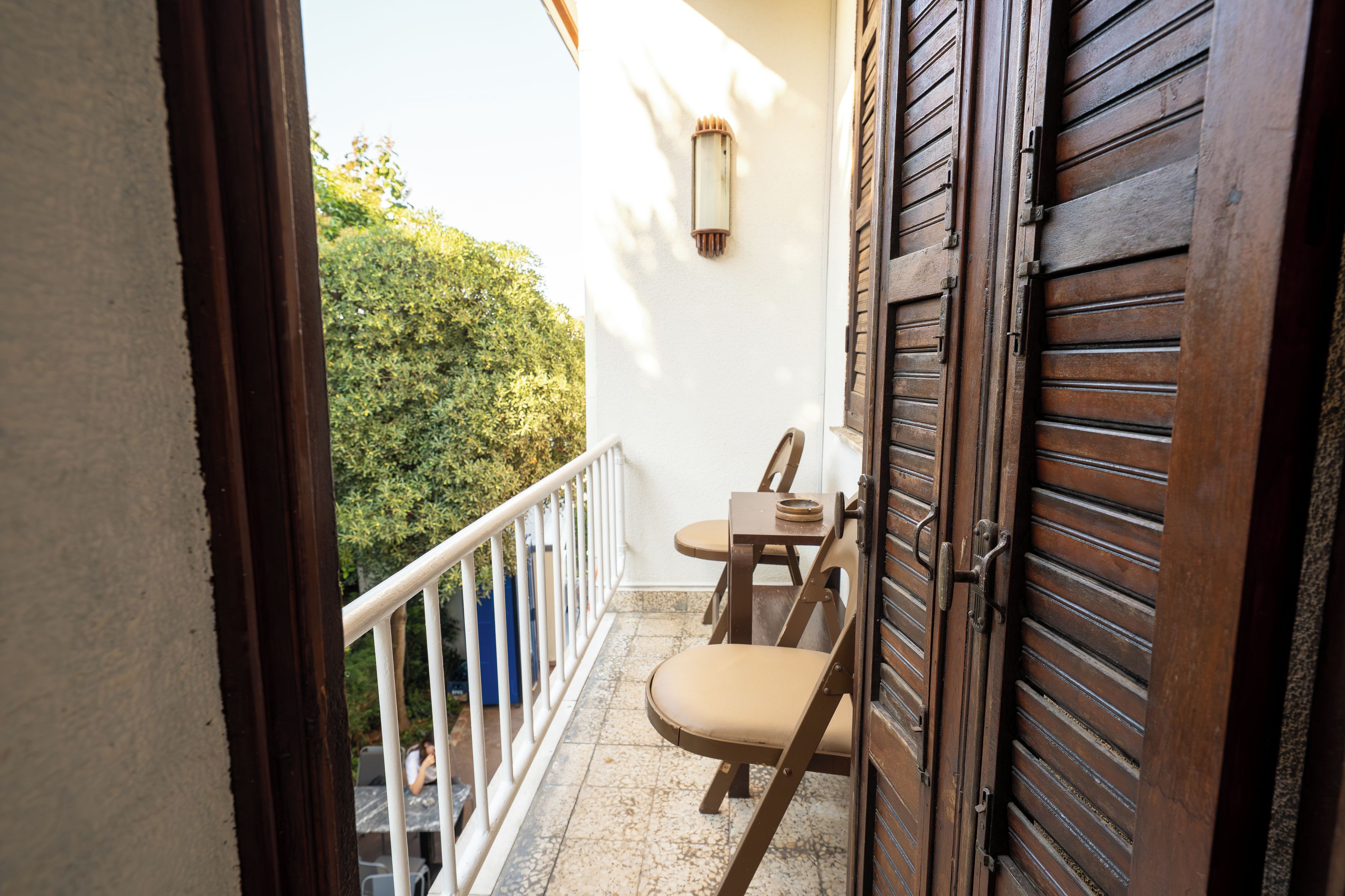 A balcony with a wooden door, a small table, and a chair.