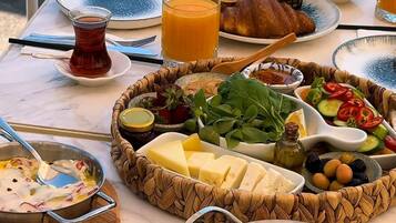 A table with various food items and drinks, including cheese, olives, and a glass of orange juice.