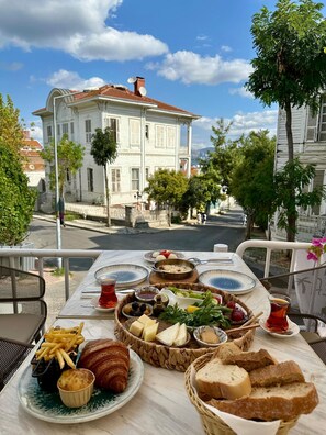 A table with food, a view of a street, and a building in the background. - Palm Villa  (Adalar)