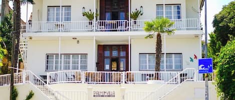A two-story building with a balcony on the upper floor, a staircase leading to the entrance, and a bicycle parked at the base.