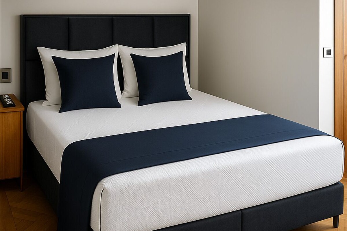A modern bed with a dark headboard, white bedding, and a dark blue accent.