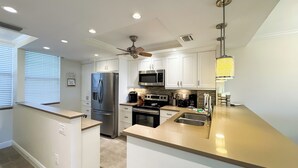 A modern kitchen with white cabinets, stainless steel appliances, a built-in oven, and a microwave. - South Seas Tower 3-401: Marco Island Rental Properties (Marco Island)