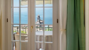 A room with a view of the sea, a balcony with wicker furniture, and a table with a white tablecloth. - Room 'Gemme Suite Bb' with Lake View, Balcony and Wi-Fi (Torri del Benaco)
