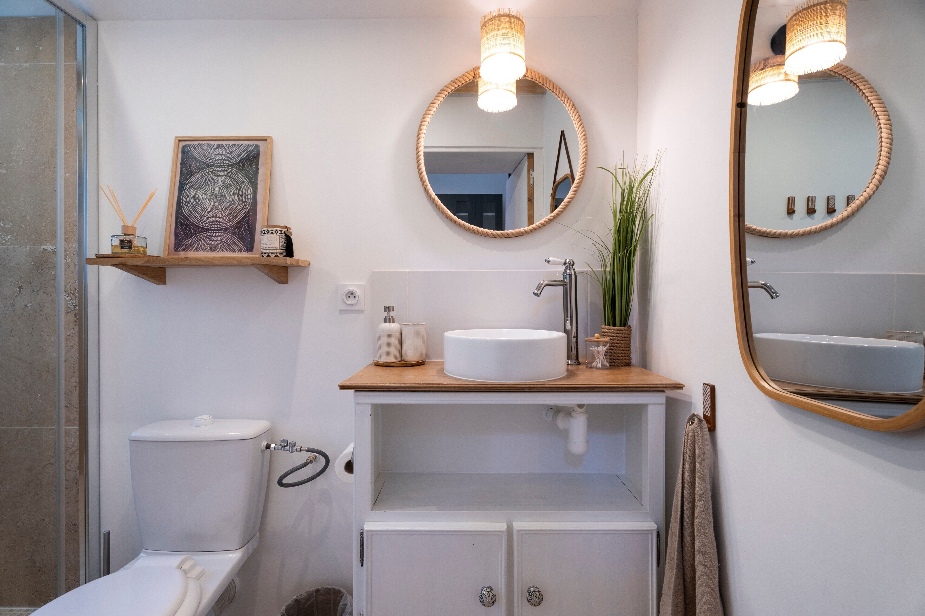 A bathroom with a toilet, sink, mirror, and towel rack.