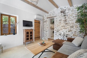A living room with a stone wall, wooden furniture, a TV, and a window with a view.