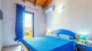 A bedroom with a bed, nightstands, a lamp, an air conditioner, and a curtain. - Holiday Home 'Elisa' with Wi-Fi and Air Conditioning (Viddalba)