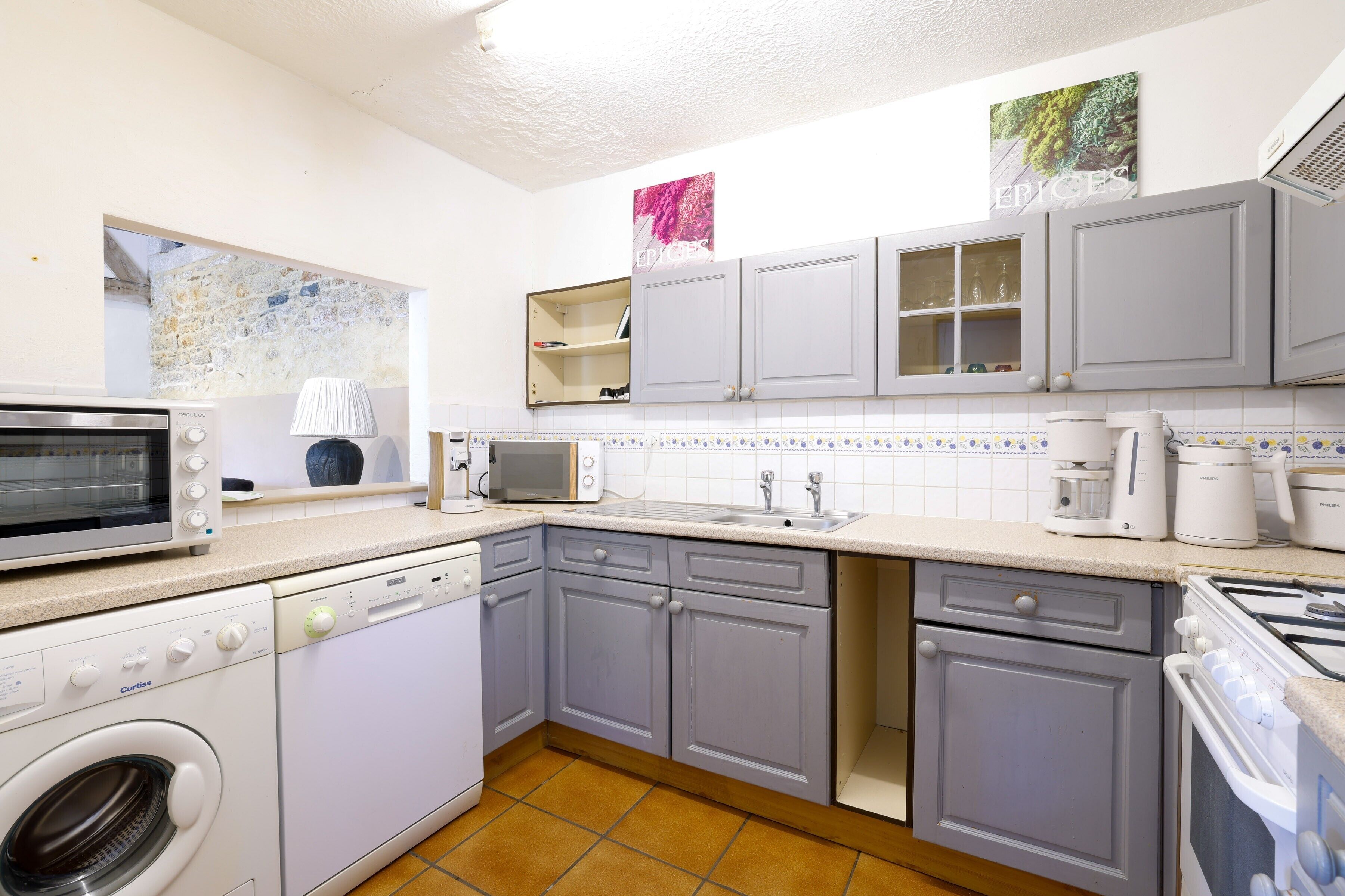 A compact kitchen with a washing machine, microwave, stove, and sink.