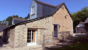 A stone building with a gabled roof, a small porch, and a single window.