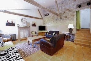 A living room with a sofa, a coffee table, a television, and a fireplace.