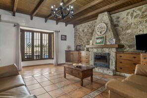 A living room with a stone fireplace, wooden furniture, and a television.