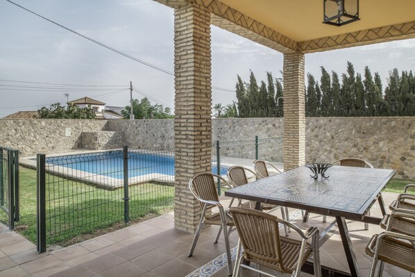 A patio area with a pool, stone walls, and outdoor furniture.
