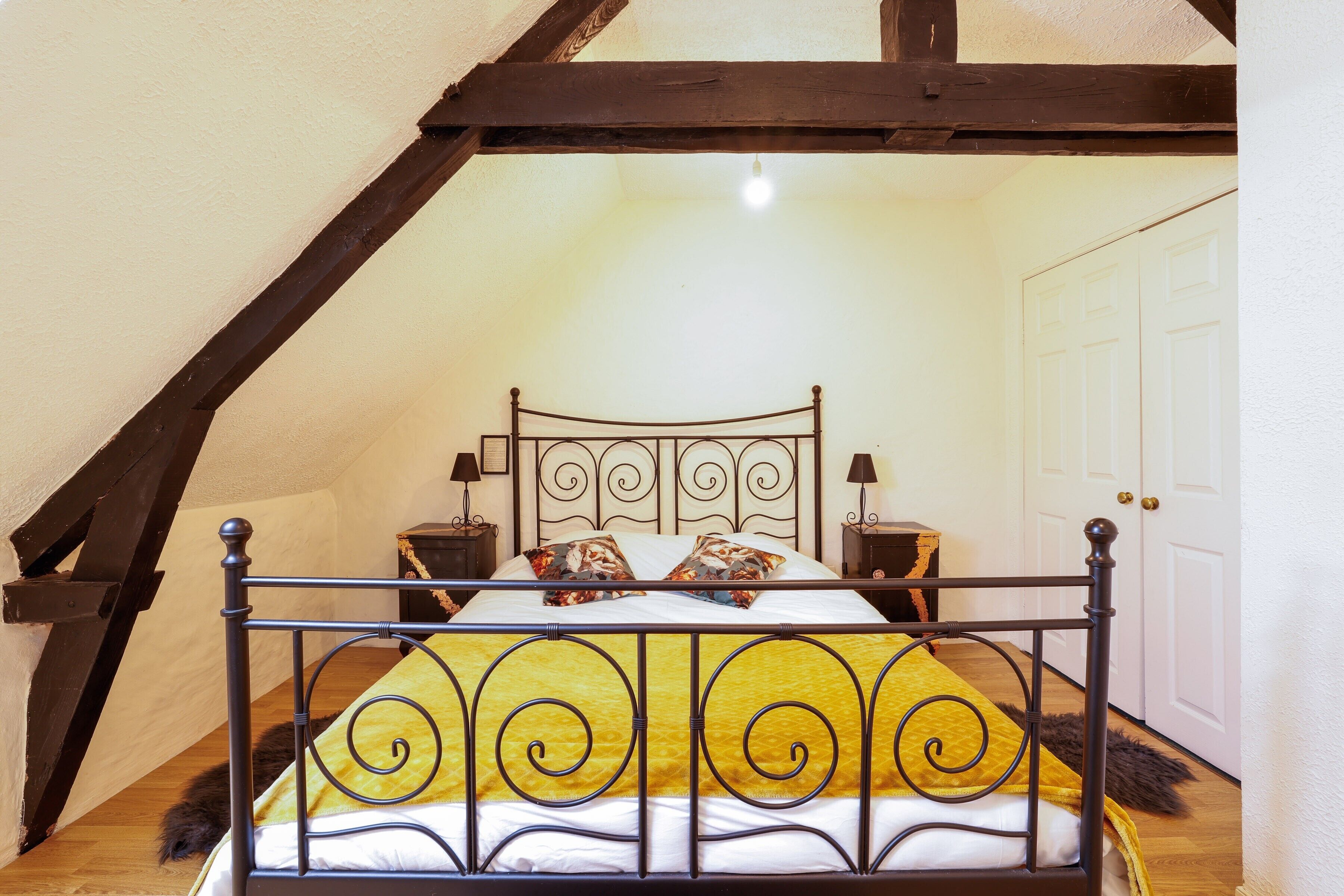 A bed with a metal frame, two bedside tables, and a white door in the background.