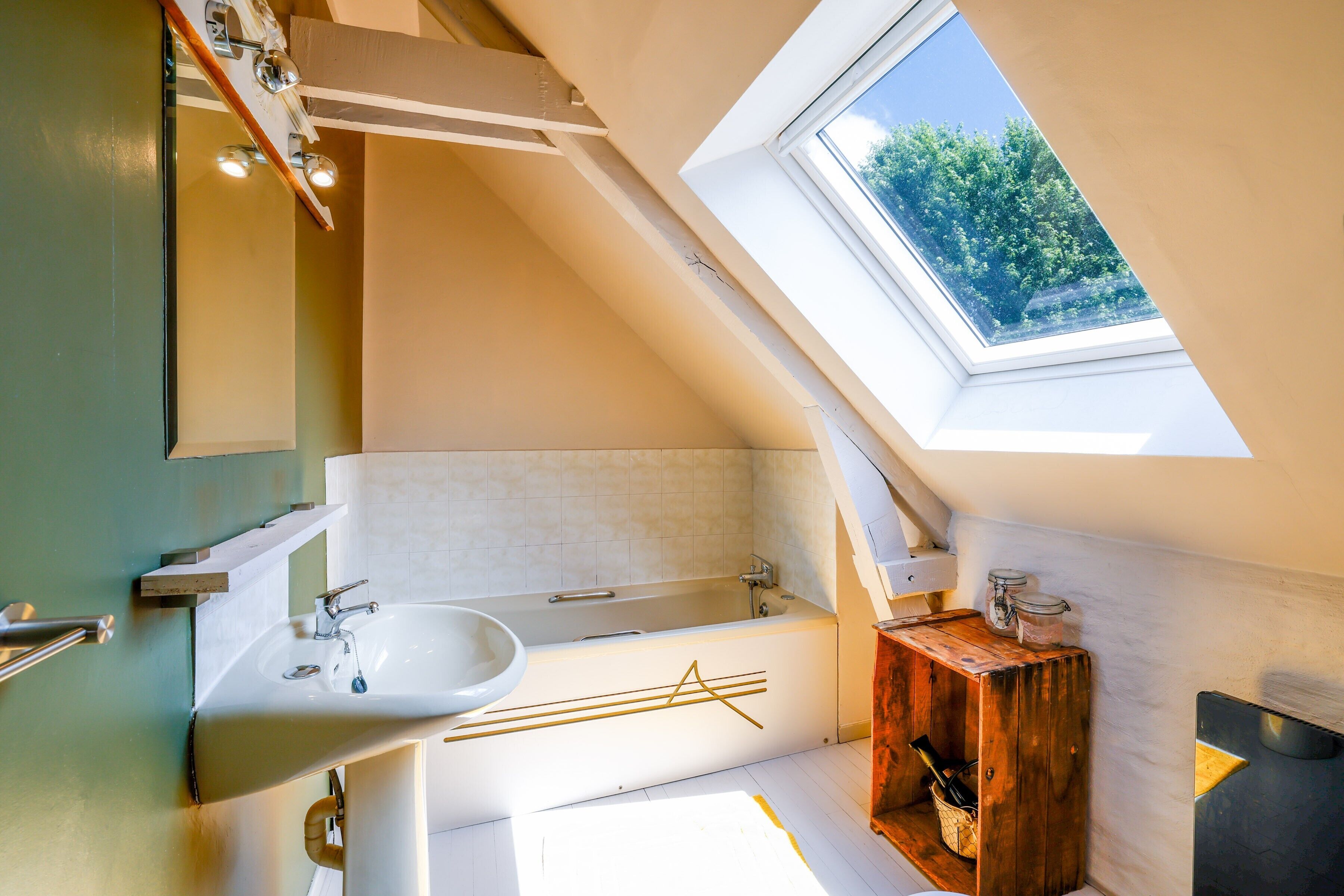 A modern bathroom with a skylight, a bathtub, a sink, and a wooden cabinet.