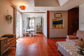 Un grand espace de vie comprenant une table à manger, un canapé et une cuisine en arrière-plan.