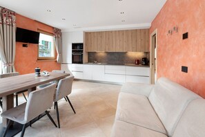A modern kitchen with wooden cabinets, a dining area with a table and chairs, and a sofa.