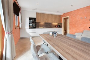 Una cocina moderna con armarios de madera, una mesa de comedor con sillas y una cafetera.