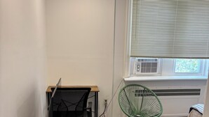 Un espace de travail comprenant un bureau, une chaise et une fenêtre avec des stores.