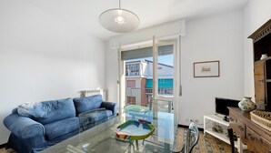 Un salon avec une table basse en verre, un canapé bleu, un meuble en bois et un téléviseur.
