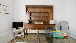 Une pièce comprenant un bureau en bois, un écran d’ordinateur, un tapis en forme de poisson et une chaise.