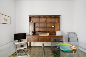 Una habitación con un escritorio de madera, un monitor de computadora, un tapete con forma de pez y una silla.