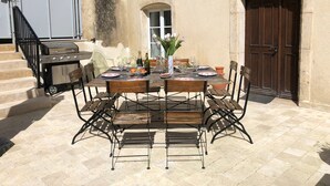 An outdoor dining area with a table set for four, surrounded by metal chairs, a grill, and a door. - Bed and Breakfast 'Double' with Shared Terrace, Private Garden and Wi-Fi (Rollainville)