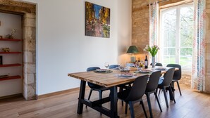 A dining area with a wooden table, black chairs, and a cityscape painting on the wall. - Bed and Breakfast 'Double' with Shared Terrace, Private Garden and Wi-Fi (Rollainville)