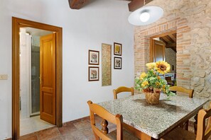 Un'area pranzo con tavolo, sedie, un vaso di fiori e quadri appesi al muro.