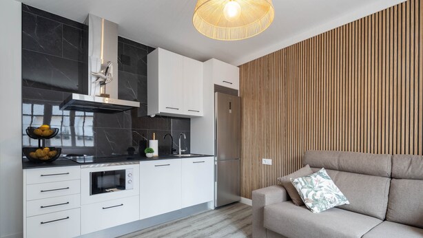 A modern kitchen with white cabinets, a built-in oven, and a stainless steel refrigerator.