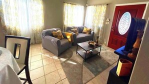 A living room with two sofas, a coffee table, and a red door with a window.