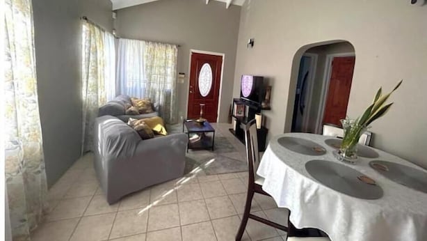 A living room with a sofa, a dining table, and a ceiling fan.