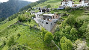 Un hotel en la ladera con arquitectura moderna, jardines en terrazas y un muro de piedra de contención.