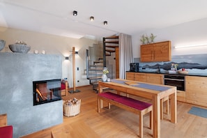 A modern kitchen with wooden cabinets, a built-in stove, and a dining area with a bench.
