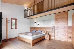 Une chambre à coucher avec un lit en bois, une table de chevet, une lampe fixée au mur et une armoire en bois.