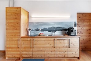 A wooden kitchen with a mountain view, a coffee machine, and a kettle.