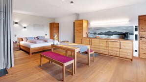 A modern room with a bed, a dining table, a bench, a wooden cabinet, and a painting of mountains. - Studio 'Röfen Mittelröfen' with Mountain View, Shared Terrace and Wi-Fi (Rovena)