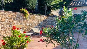 A patio with stone walls, potted plants, and outdoor furniture.